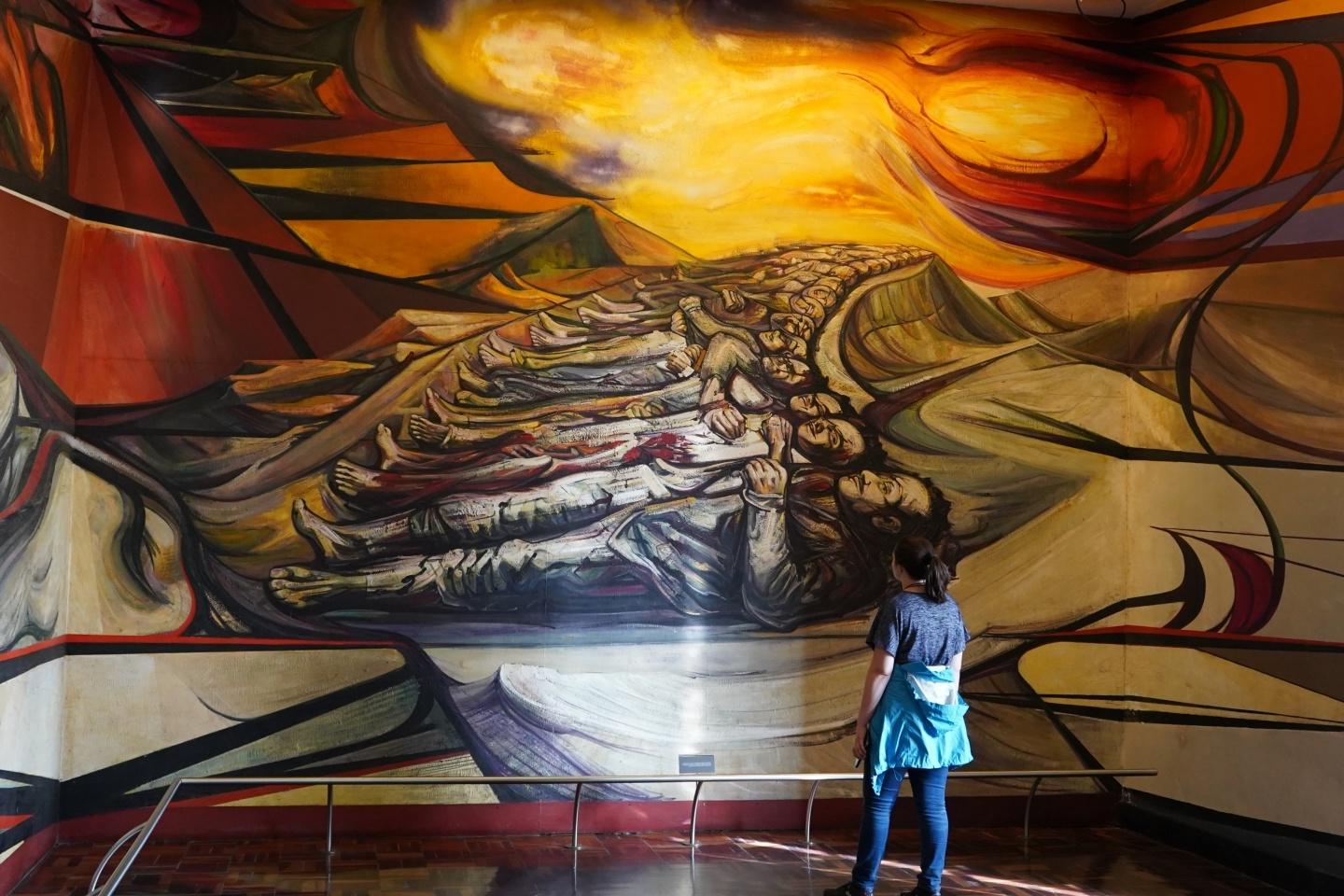 Student gazing at a huge Spanish mural at an exhibit 