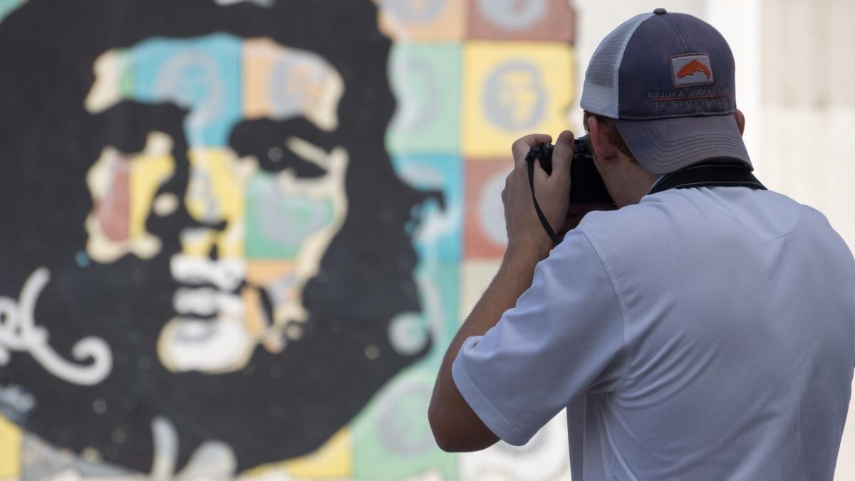Man takes photo of Che Guevara mural in Cuba.