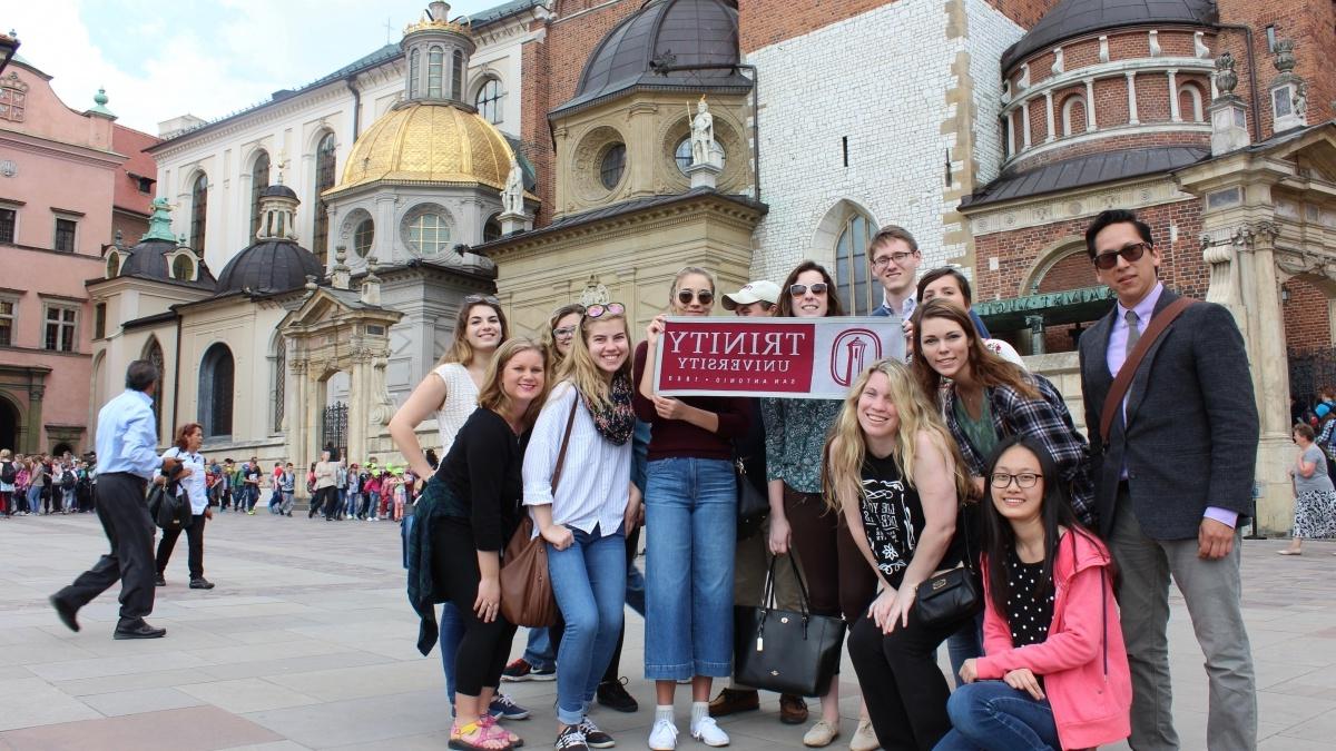 Students abroad pose with Trinity University banner.